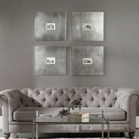 Gray tufted sofa in a living room with four metallic-framed artworks on the wall.