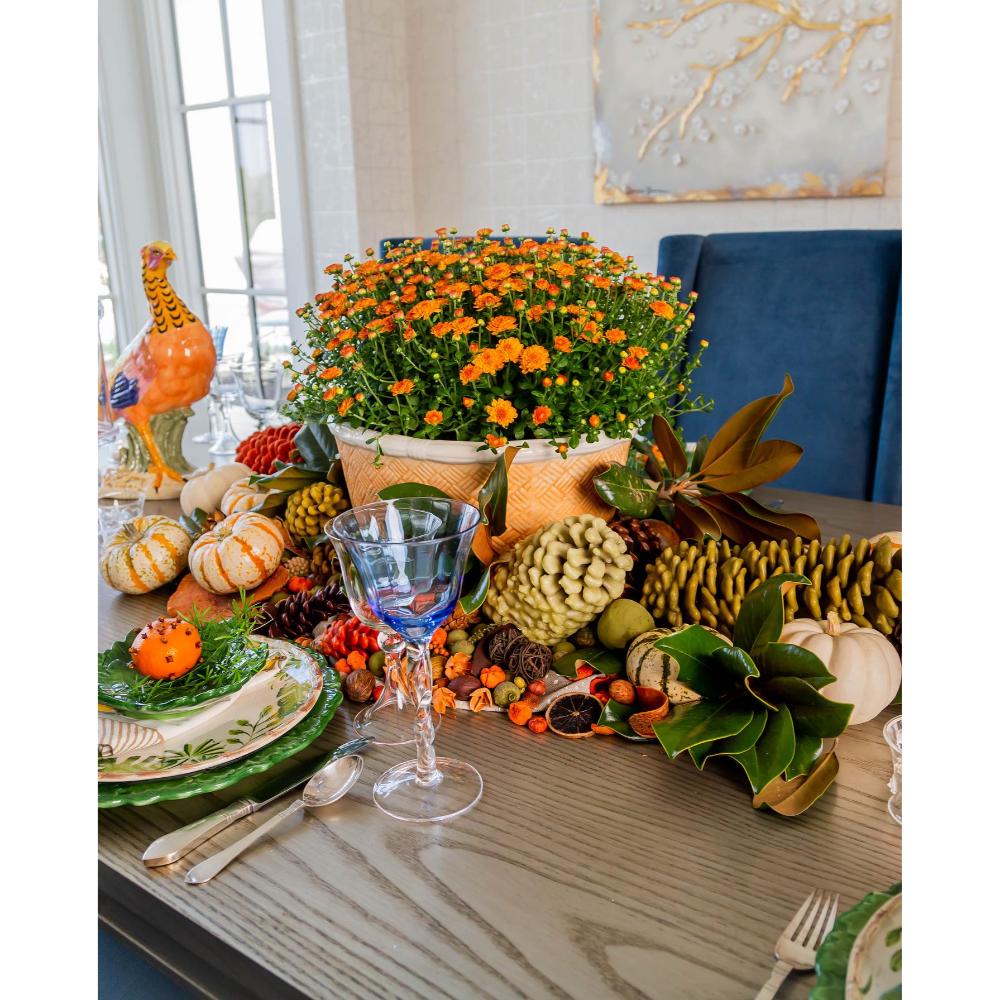 Decorative Thanksgiving table setting with pumpkins, flowers, and glasses.