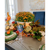 Decorative Thanksgiving table setting with pumpkins, flowers, and glasses.