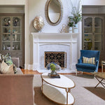Elegant living room with a white fireplace, Dessau Home's Circles Fireplace Screen, blue chair, beige sofa, and coffee table.
