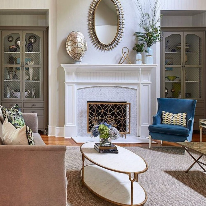 Elegant living room with a white fireplace, Dessau Home's Circles Fireplace Screen, blue chair, beige sofa, and coffee table.