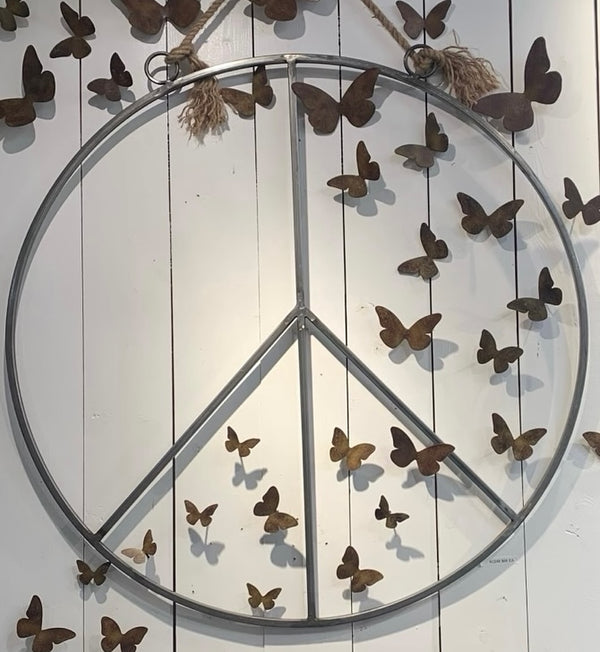 Sugarboo & Co. Hanging Metal + Jute Peace Sign displayed on a white wall with decorative butterflies.