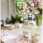 Decorative table setting with floral arrangement, plates, and glasses on a white tablecloth.