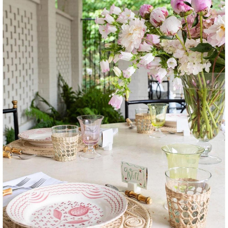 Decorative table setting with floral arrangement, plates, and glasses on a white tablecloth.