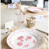 Table setting with floral plates, glasses, and cutlery on a light surface.
