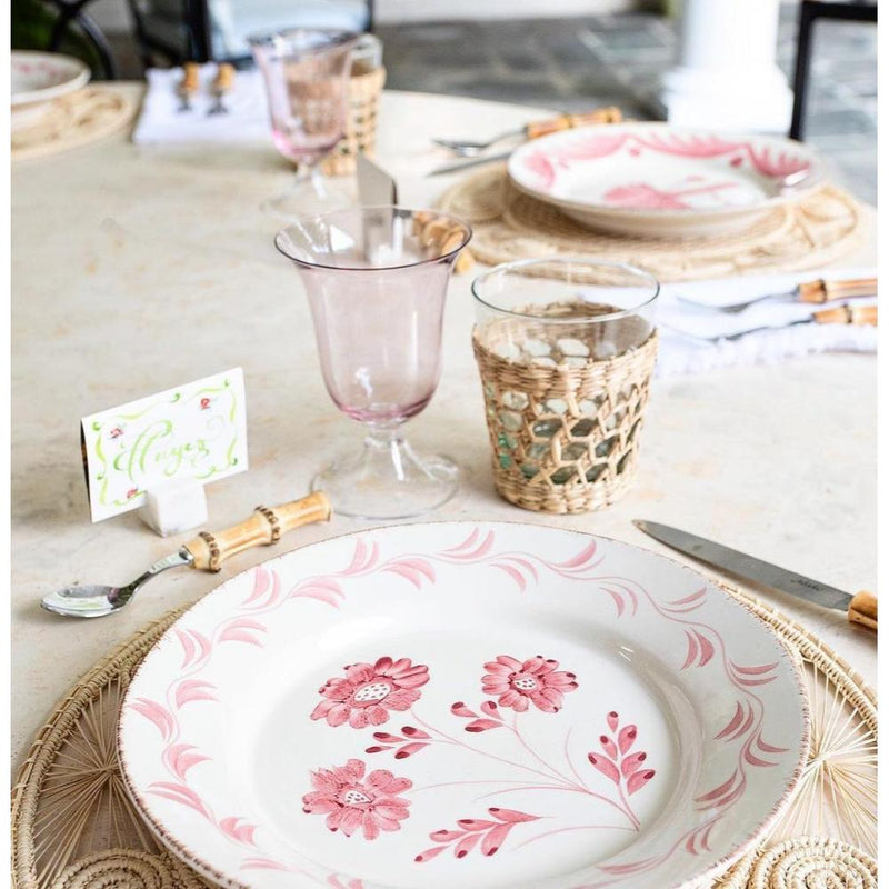 Table setting with floral plates, glasses, and cutlery on a light surface.