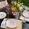 Outdoor table setting with floral centerpiece, plates, glasses, and cutlery.