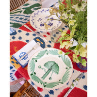 Colorful table setting with decorative plates and flowers on a patterned tablecloth.