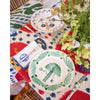 Colorful table setting with decorative plates and flowers on a patterned tablecloth.