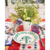 Dining table setting with floral centerpiece, colorful tablecloth, and patterned plates.