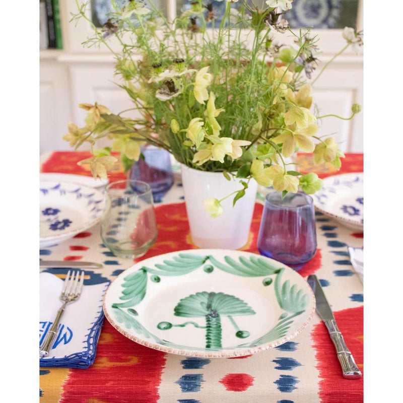 Dining table setting with floral centerpiece, colorful tablecloth, and patterned plates.