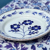 Decorative plate with blue floral design on a matching tablecloth, featuring the brand 'Abigails'.