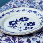 Decorative plate with blue floral design on a matching tablecloth, featuring the brand 'Abigails'.