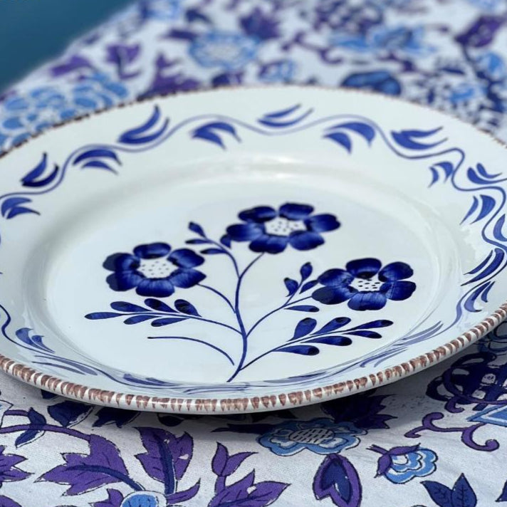 Decorative plate with blue floral design on a matching tablecloth, featuring the brand 'Abigails'.
