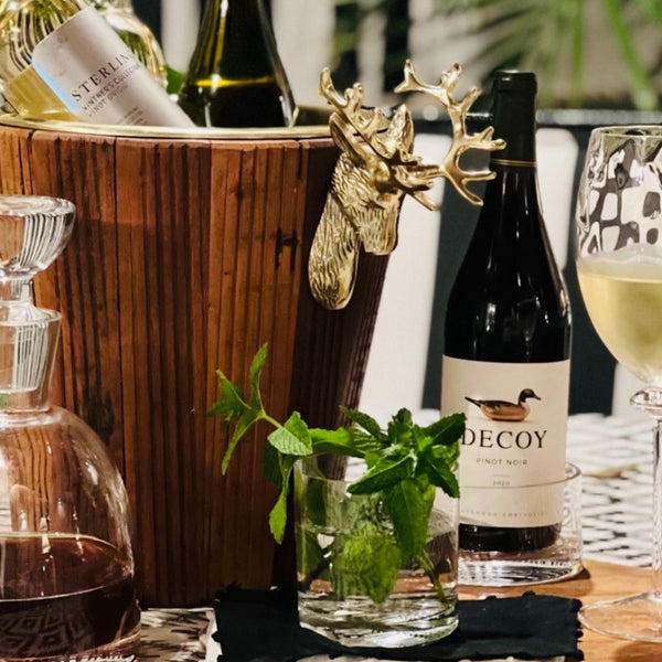 Wine bottle labeled 'Decoy' with an ice bucket and glasses on a table.