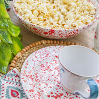 Bowl of popcorn on a table with a mug and decorative items.