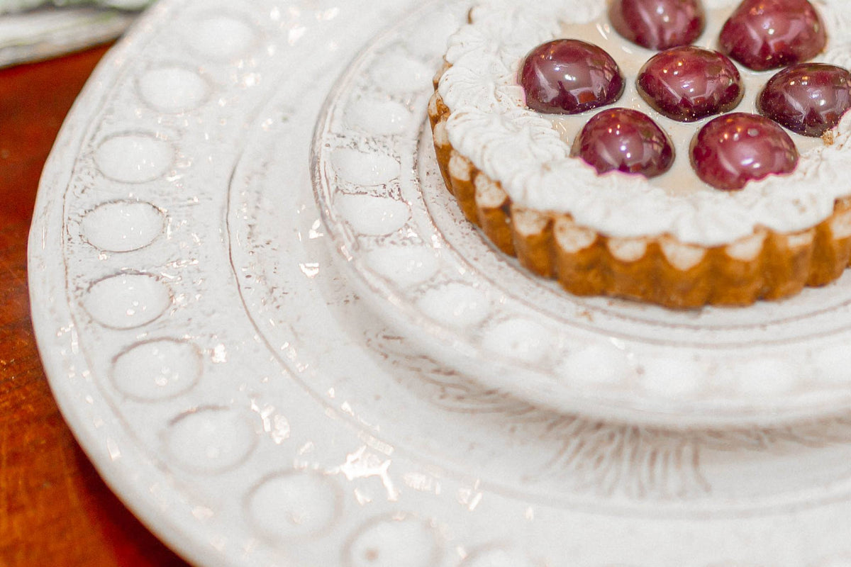 Small tart with grapes on a decorative white plate