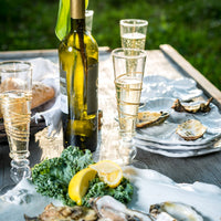 A table set with wine, oysters, bread, and Abigails Razzle Dazzle Gold Icon Footed Champagne Flutes (set of 6).