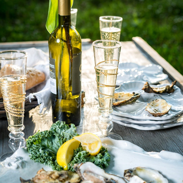 A table set with wine, oysters, bread, and Abigails Razzle Dazzle Gold Icon Footed Champagne Flutes (set of 6).