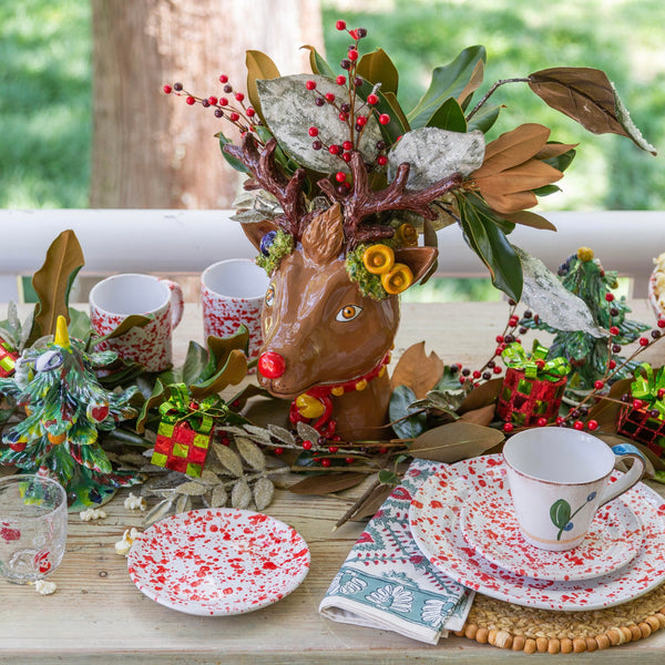Decorative table setting with reindeer head, mugs, and plates on a wooden surface.