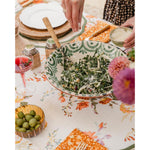Dining table with a bowl of salad, olives, and a floral tablecloth.