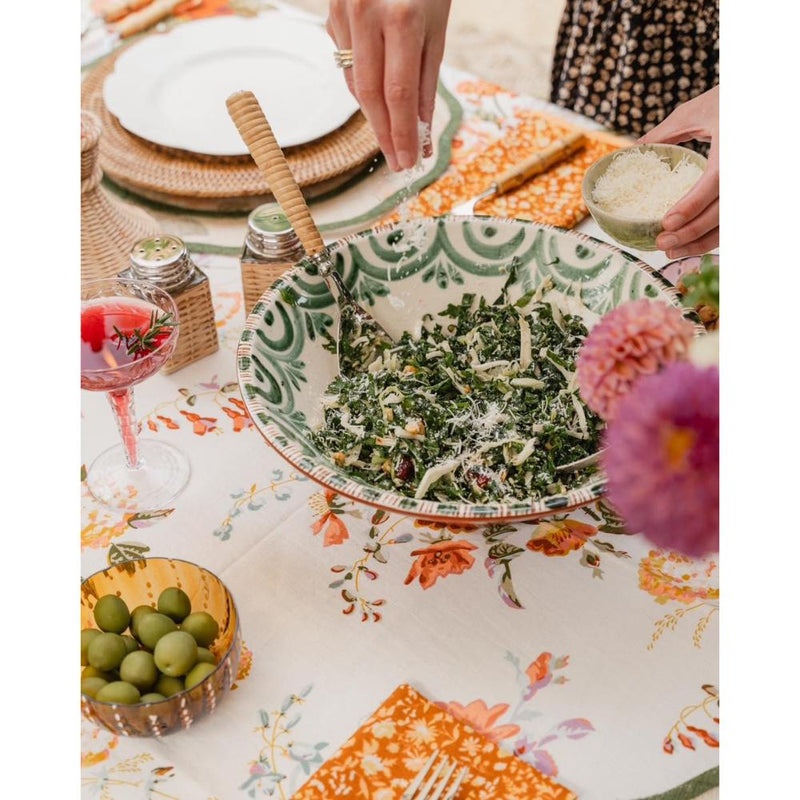 Dining table with a bowl of salad, olives, and a floral tablecloth.