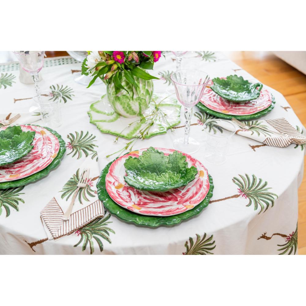 Table set with floral plates, green leaf bowls, and Abigails' Compagnia Green Oak Leaf Charger on a leafy tablecloth.