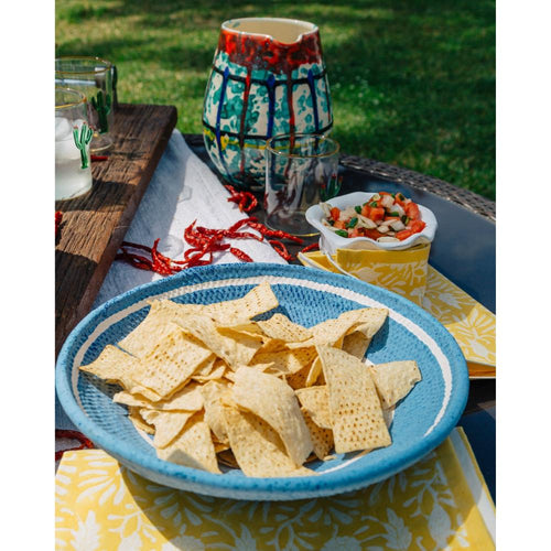 A blue bowl of tortilla chips sits on Abigails Tuscan Sun Cabana Napkins (set of 8) beside salsa and drinks outdoors.