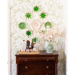 Wooden dresser with decorative items against a floral wallpapered wall