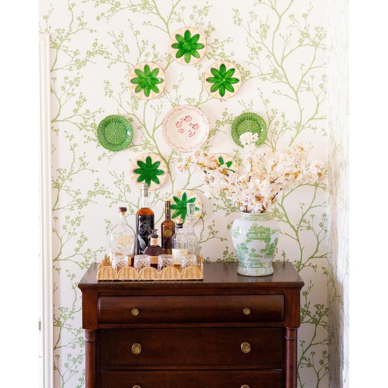 Wooden dresser with decorative items against a floral wallpapered wall