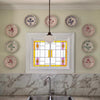 A kitchen wall with Casa Nuno Blue Pomegranate plates by Abigails around a stained glass window above a marble sink.