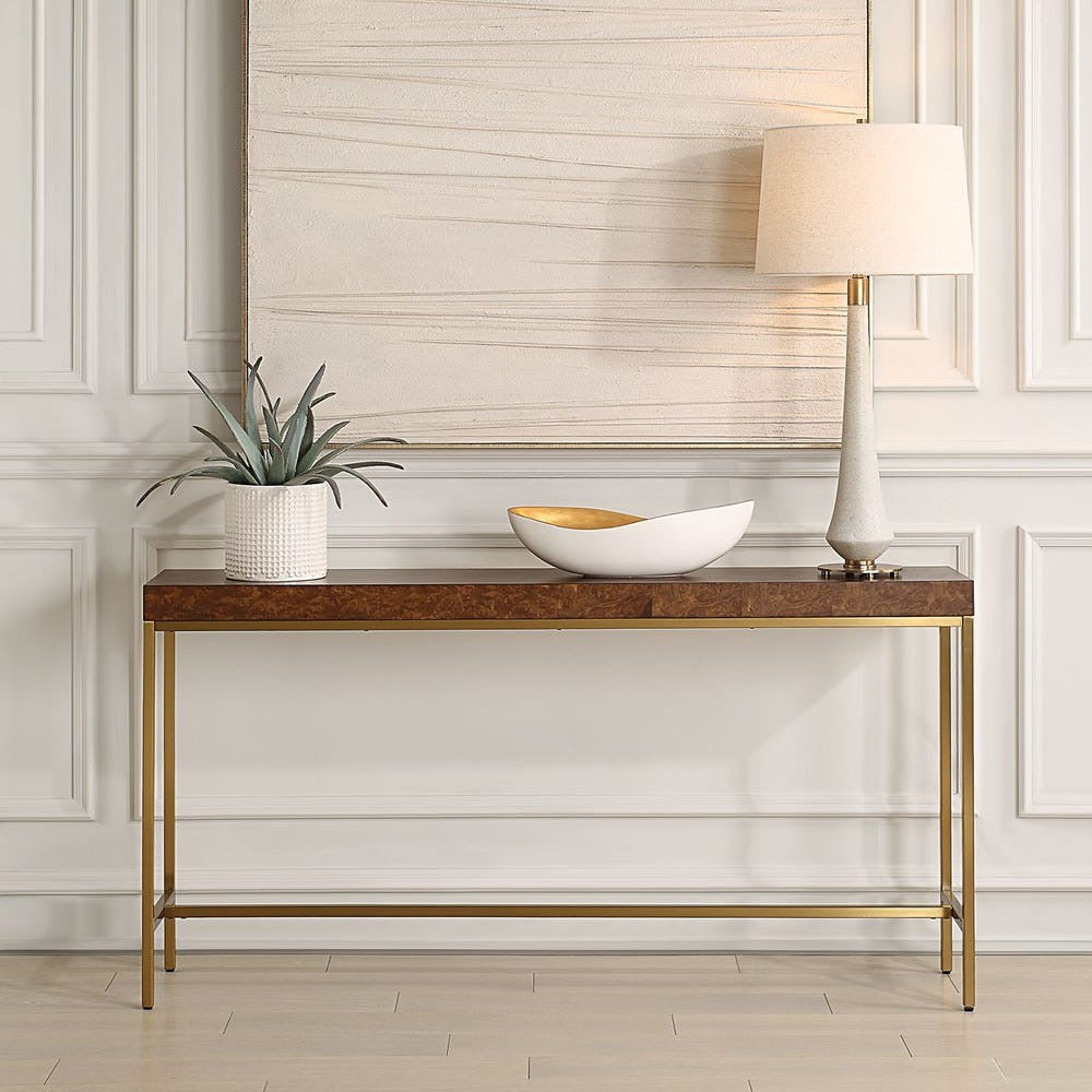 Console table with decorative items in a room with light-colored walls and wooden floor.