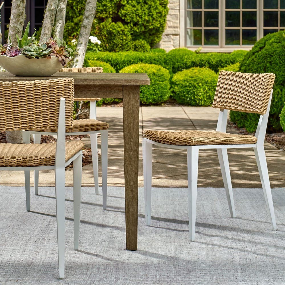 Outdoor dining set with wooden table and wicker chairs on a patio.
