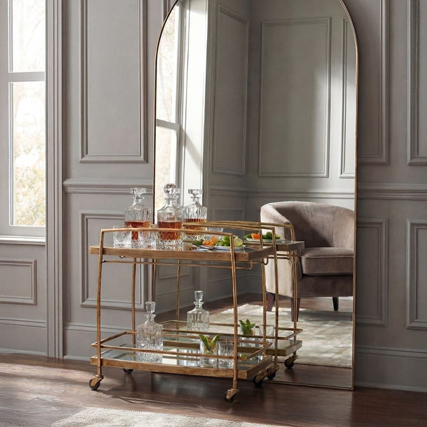 Decorative bar cart with drinks and snacks in a stylish room with a large mirror.
