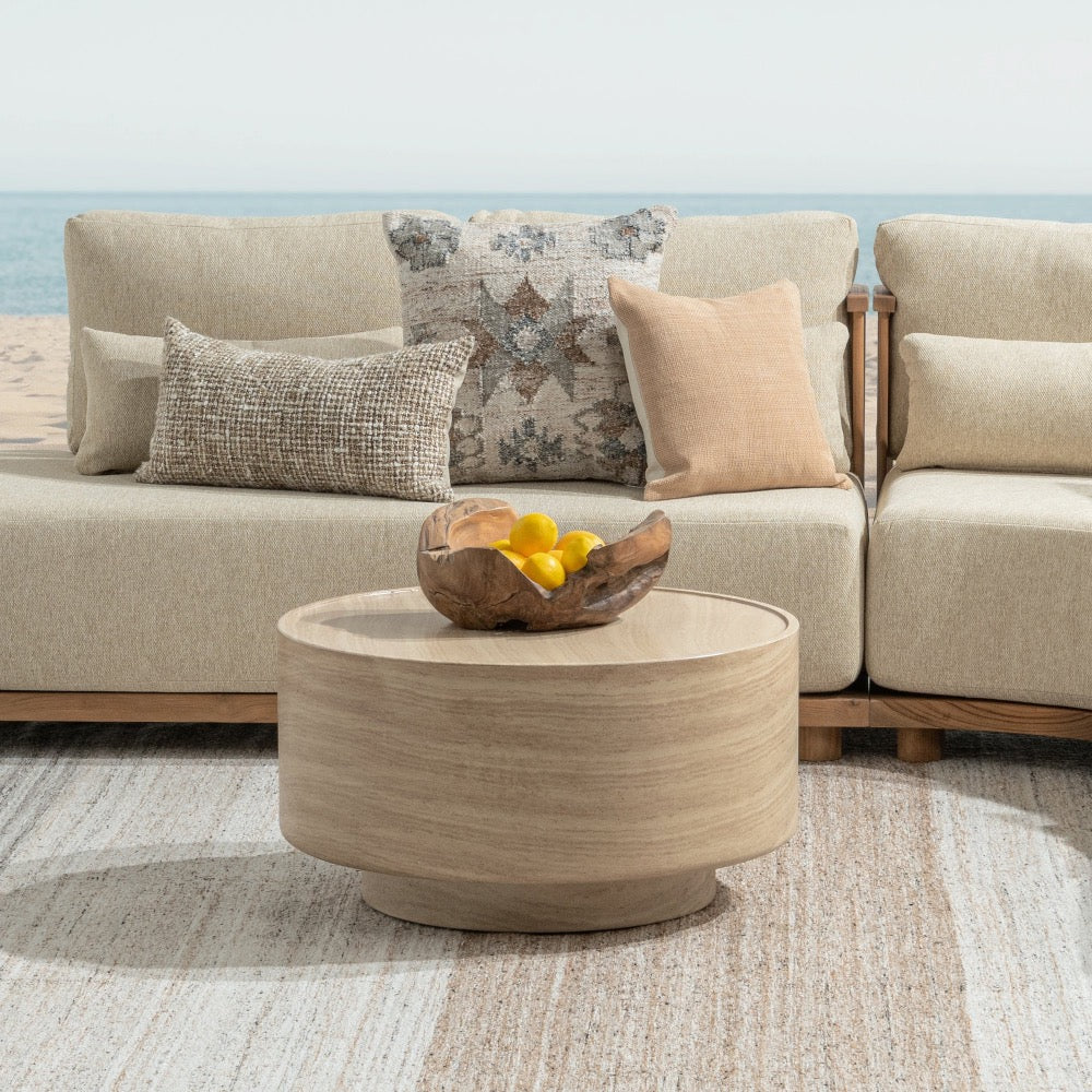 Beige sofa with decorative pillows and a beige stone coffee table in a living room setting.