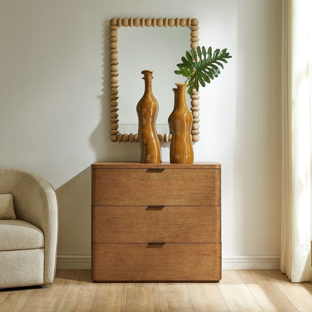 Wooden dresser with three drawers, two vases, and a mirror in a room setting.