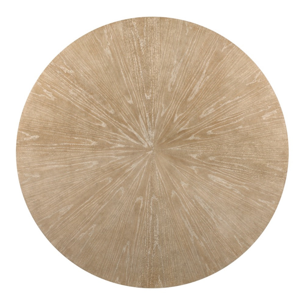 Set the Aerial Rift Dining Table by Woodbridge Furniture on a beige rug with radiating lines for a sunburst-inspired look.