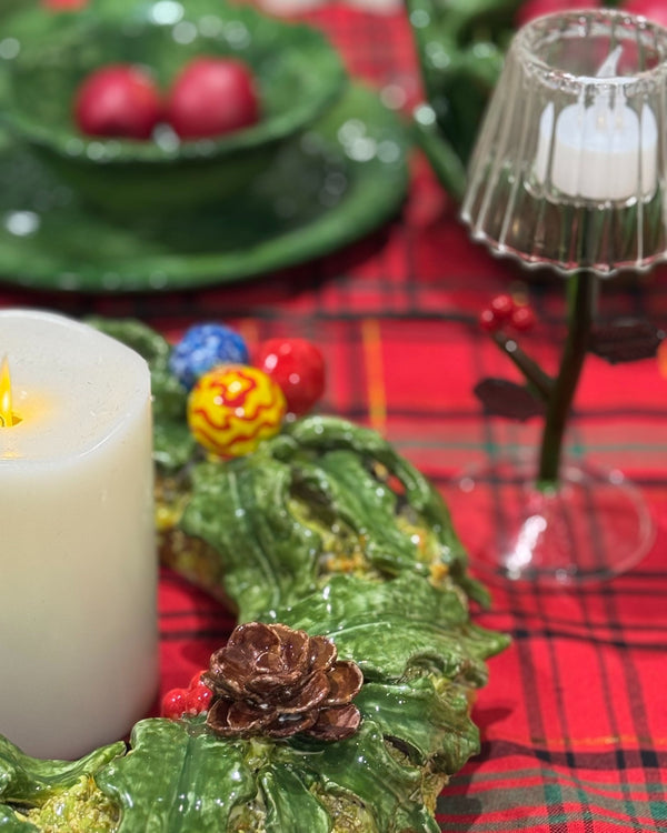 Decorative table setting with candles, green plates, and a red plaid tablecloth.