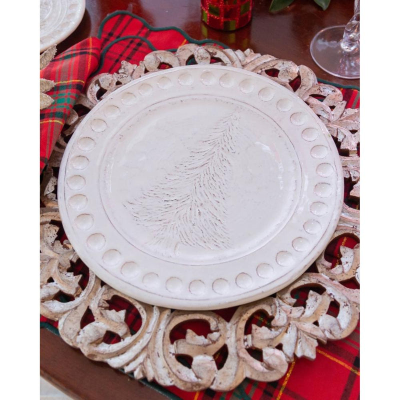 Decorative white plate with embossed design on a ornate metal stand, placed on a red plaid tablecloth.