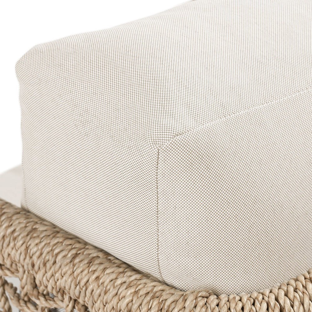 Close-up of a textured beige cushion on a woven chair.