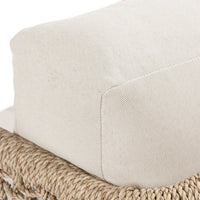 Close-up of a textured beige cushion on a woven chair.