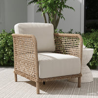 Wicker armchair with beige cushions on a patio with plants in the background
