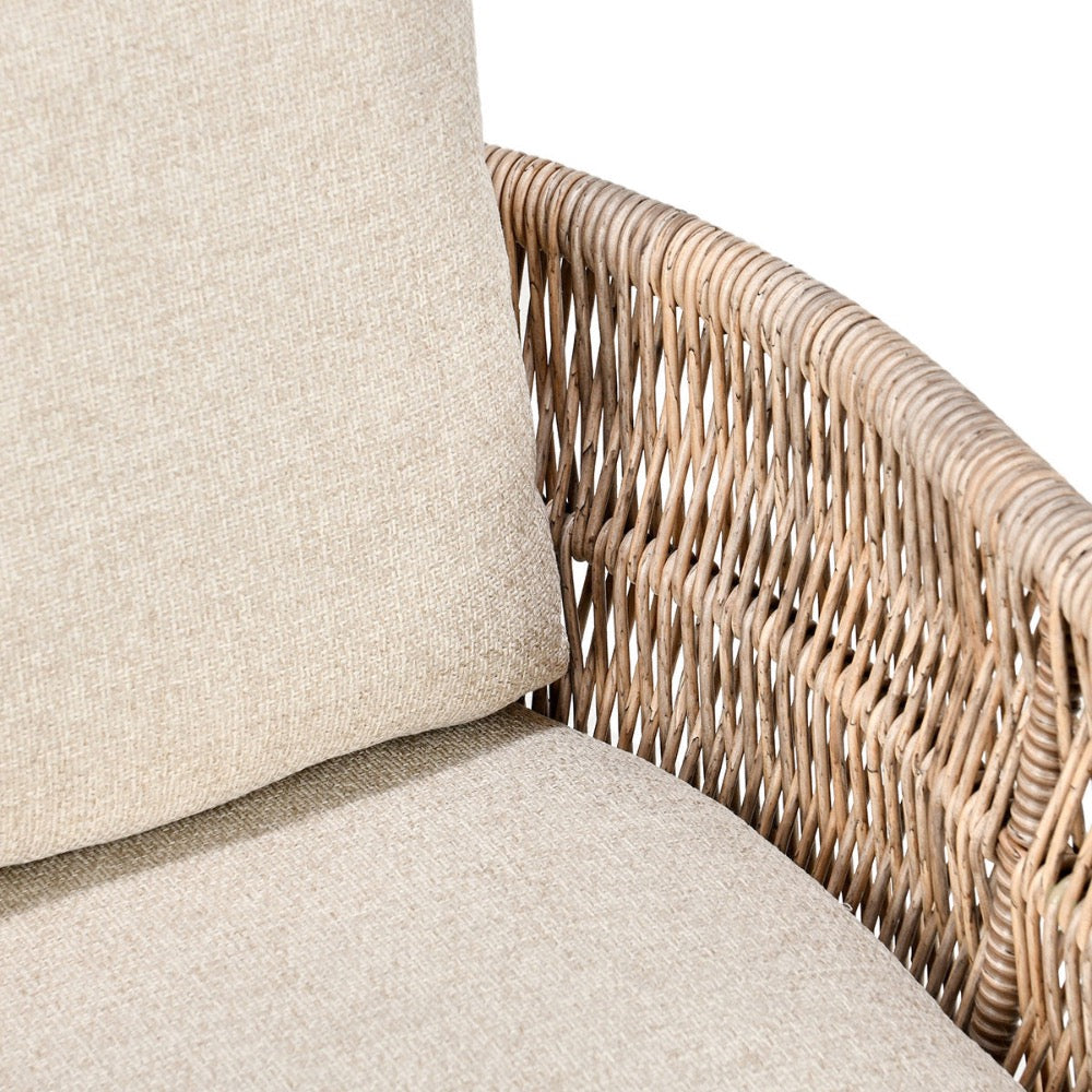 Corner of a sofa with wicker armrest and beige cushions on a white background