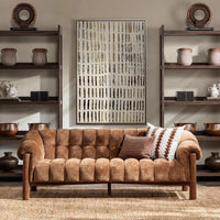 Brown sofa in a room with shelves displaying decorative items and a wall art piece.