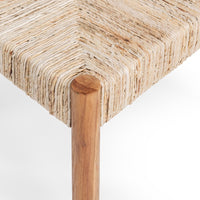 Close-up of a woven natural fiber stool or bench seat with a round wooden leg on a white background.