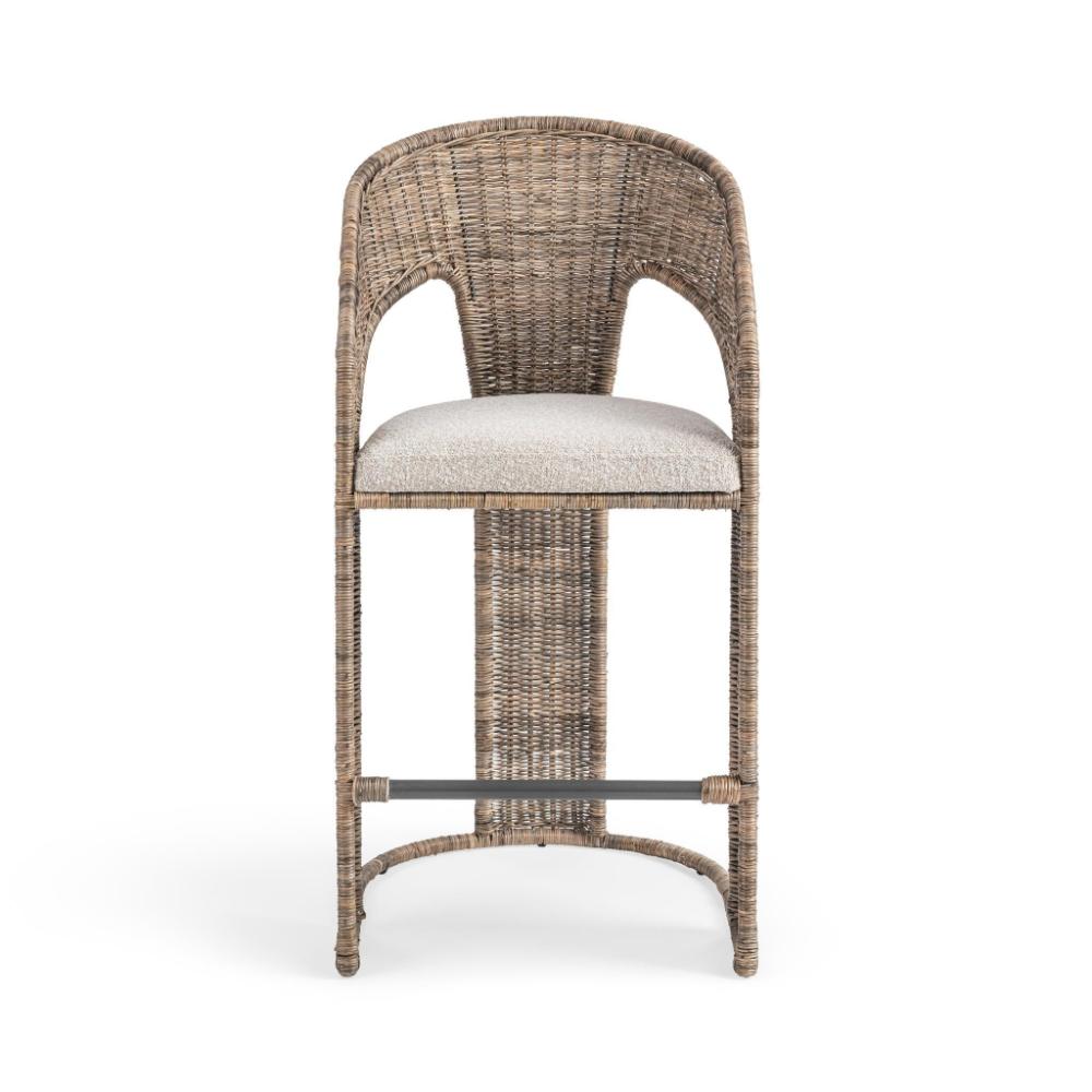 A tall wicker barstool with a curved backrest, upholstered light beige seat cushion, and a dark metal footrest bar, shown against a plain white background.