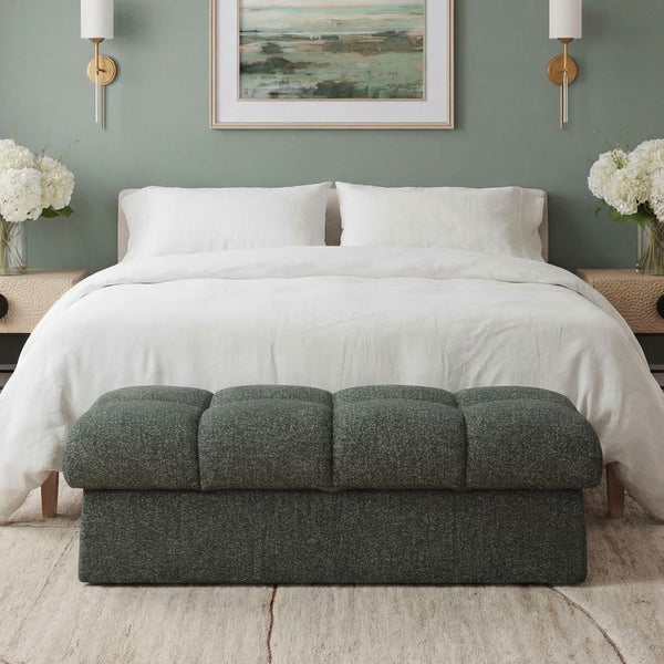 Moss green and blue ottoman in front of a bed with white bedding and a green wall.