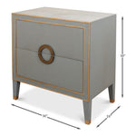 The Storm Grey Shagreen Bedside Table by Sarreid, Ltd. features a gray rectangular design with gold leather piping accents, two drawers, and round handles. Dimensions: 30" height, 30" width, 18" depth—ideal for bedside storage.