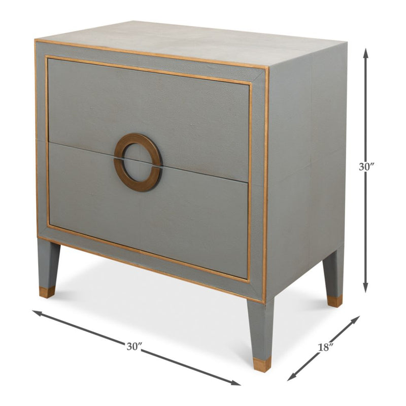 The Storm Grey Shagreen Bedside Table by Sarreid, Ltd. features a gray rectangular design with gold leather piping accents, two drawers, and round handles. Dimensions: 30" height, 30" width, 18" depth—ideal for bedside storage.