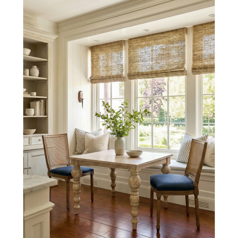 square light wood table ornate table legs two navy and wood dining chairs windows and shelving in ackground 